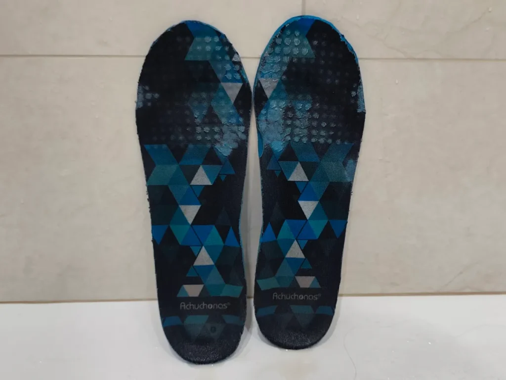 Two blue geometric patterned sneaker insoles laid side by side after cleaning