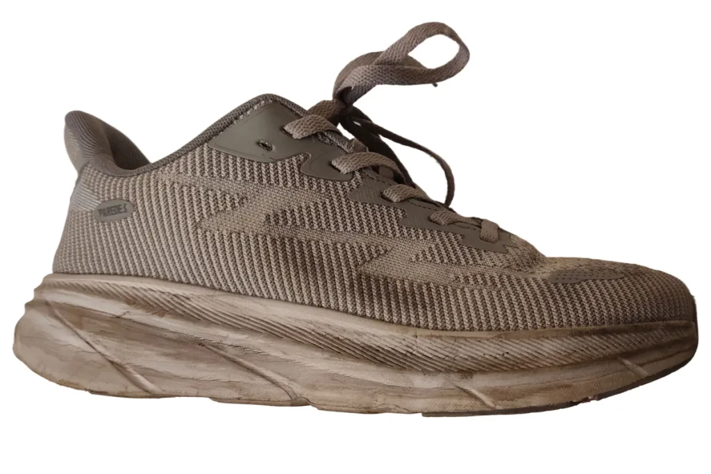 Side view of dirty grey mesh sneaker with soiled midsole before hand cleaning